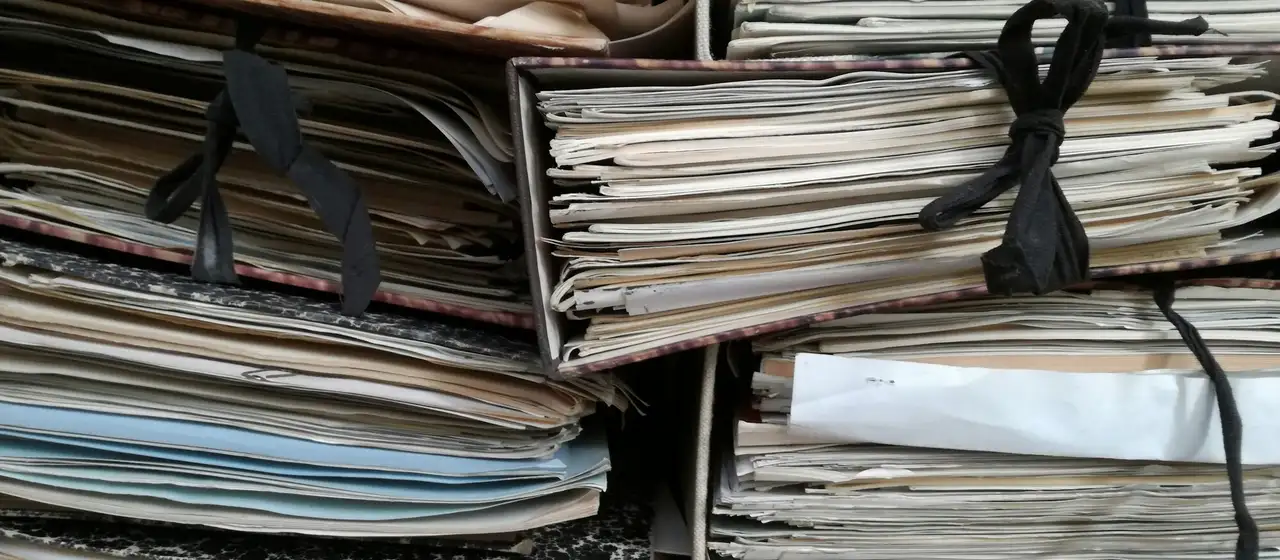 Stapels papieren dossiermappen, dichtgebonden met zwart lint.